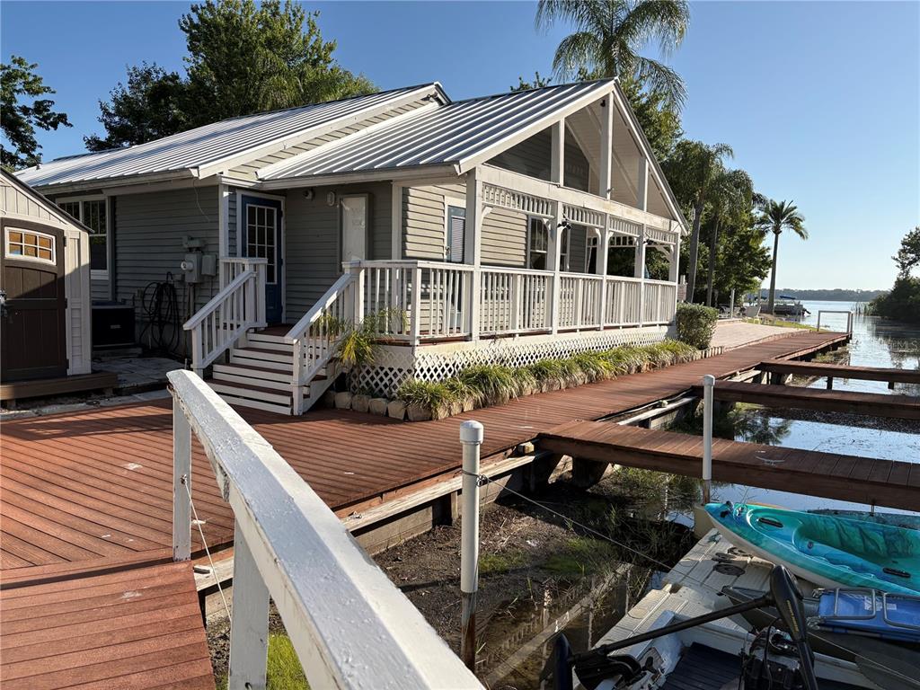 A gray house with a metal roof and a large wooden deck overlooking a lake — 2511 2511 DOLLY BAY DRIVE UNIT 102, PALM HARBOR, FL