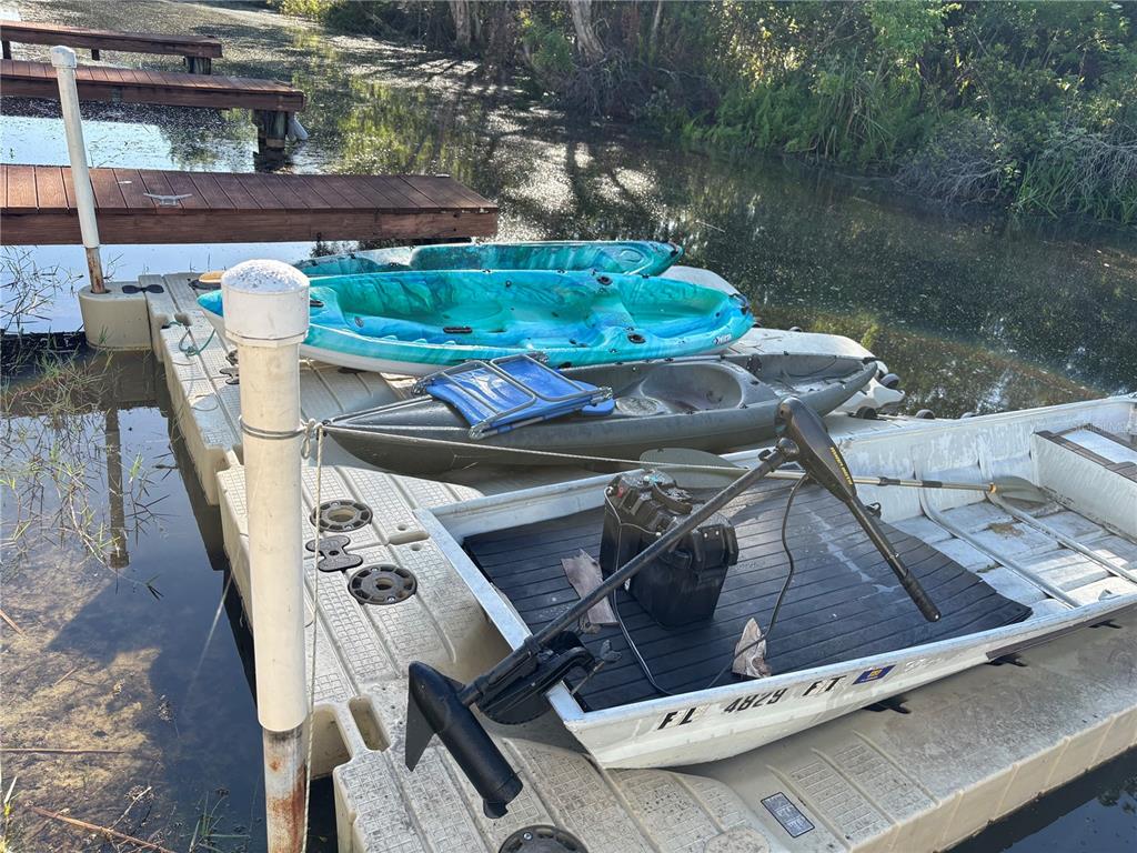 A small boat and two kayaks are docked at a floating pier on a canal — 2511 2511 DOLLY BAY DRIVE UNIT 102, PALM HARBOR, FL
