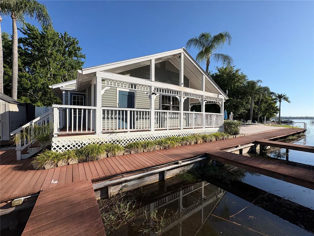 A light green cottage with a screened porch sits beside a wooden dock on water — 2511 2511 DOLLY BAY DRIVE UNIT 102, PALM HARBOR, FL
