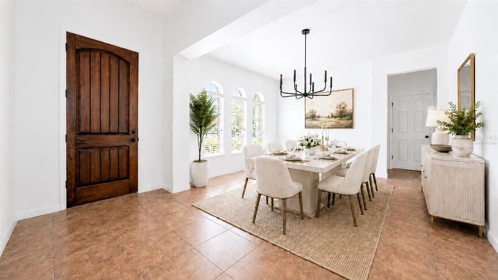 A dining room features a wooden door, tile flooring, a rectangular table, and a chandelier — 8531 GEDDES LOOP, ORLANDO, FL