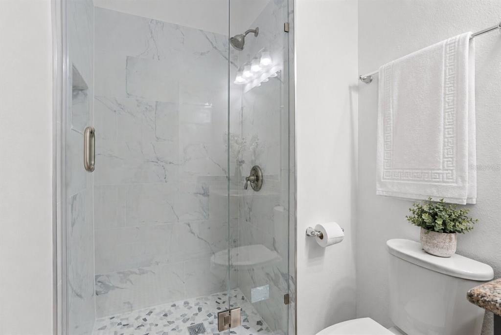 A bathroom features a glass-enclosed walk-in shower with marble-look tile and a white toilet — 8531 GEDDES LOOP, ORLANDO, FL
