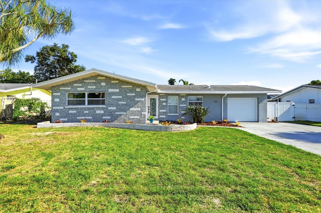 A single-story house with a gray stone facade, a white garage, and a front lawn — 1354 62ND AVENUE S, ST PETERSBURG, FL