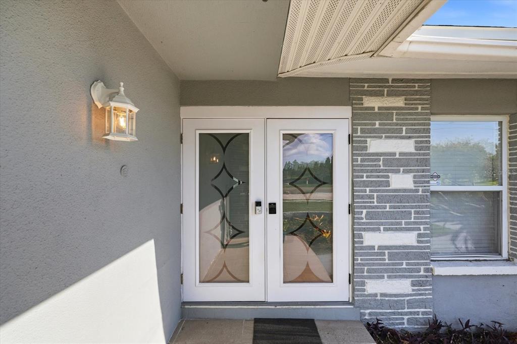 A front entrance features double glass-paneled doors, a wall-mounted light, and gray stone siding — 1354 62ND AVENUE S, ST PETERSBURG, FL