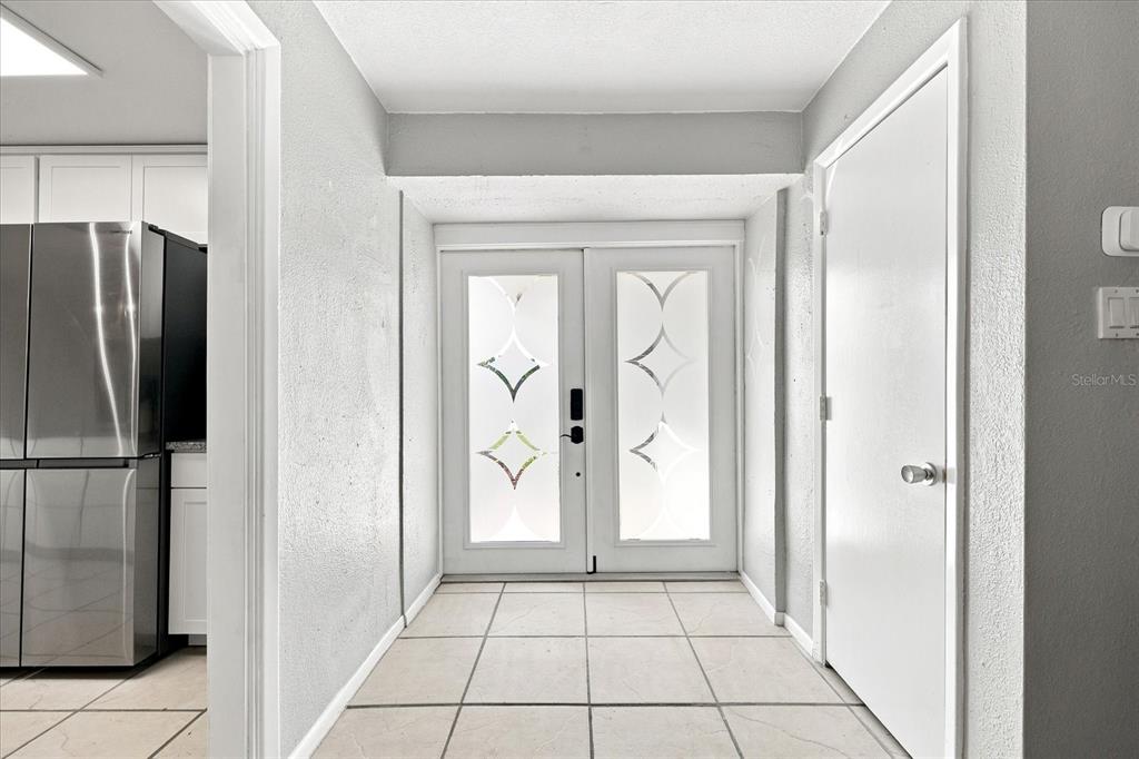 An entryway features white double doors with decorative glass panels and light-colored tile flooring — 1354 62ND AVENUE S, ST PETERSBURG, FL