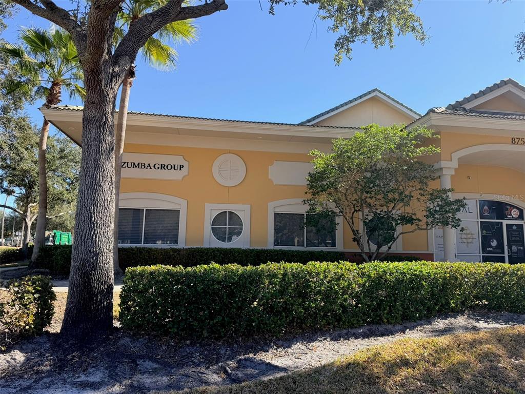 A single-story commercial building with yellow stucco walls, a tiled roof, and a hedge — 8751 COMMODITY CIRCLE UNIT 5, ORLANDO, FL