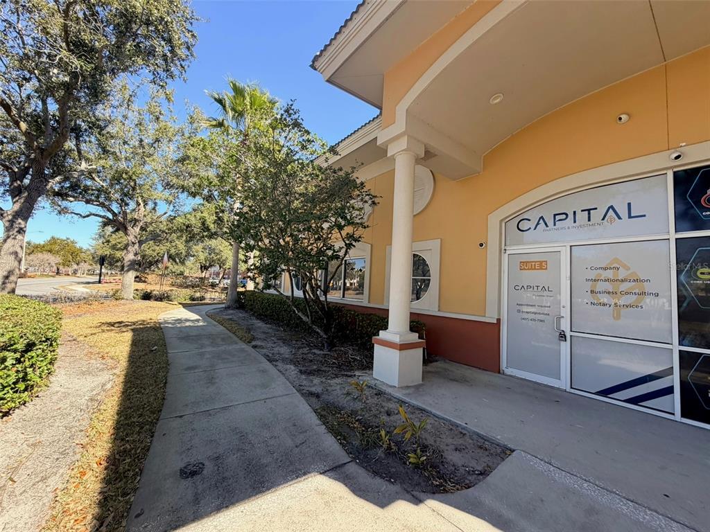 A sidewalk leads to the entrance of a commercial office suite with glass doors — 8751 COMMODITY CIRCLE UNIT 5, ORLANDO, FL