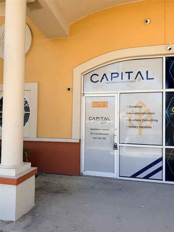 The exterior entrance to a business suite features a glass door and large window signage — 8751 COMMODITY CIRCLE UNIT 5, ORLANDO, FL