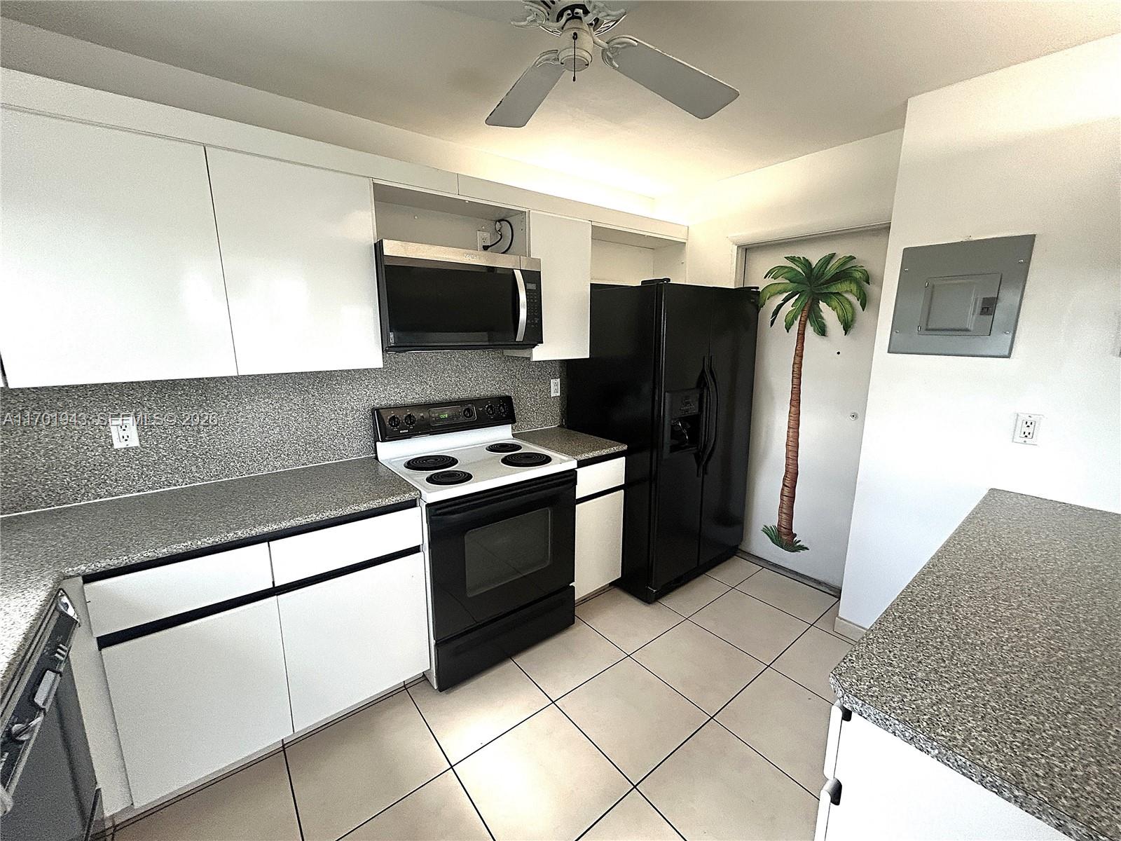 A kitchen features white cabinets, speckled countertops, a double sink, and black appliances — 1825 S Ocean Dr # 401, Hallandale Beach FL 33009, HALLANDALE BEACH, FL