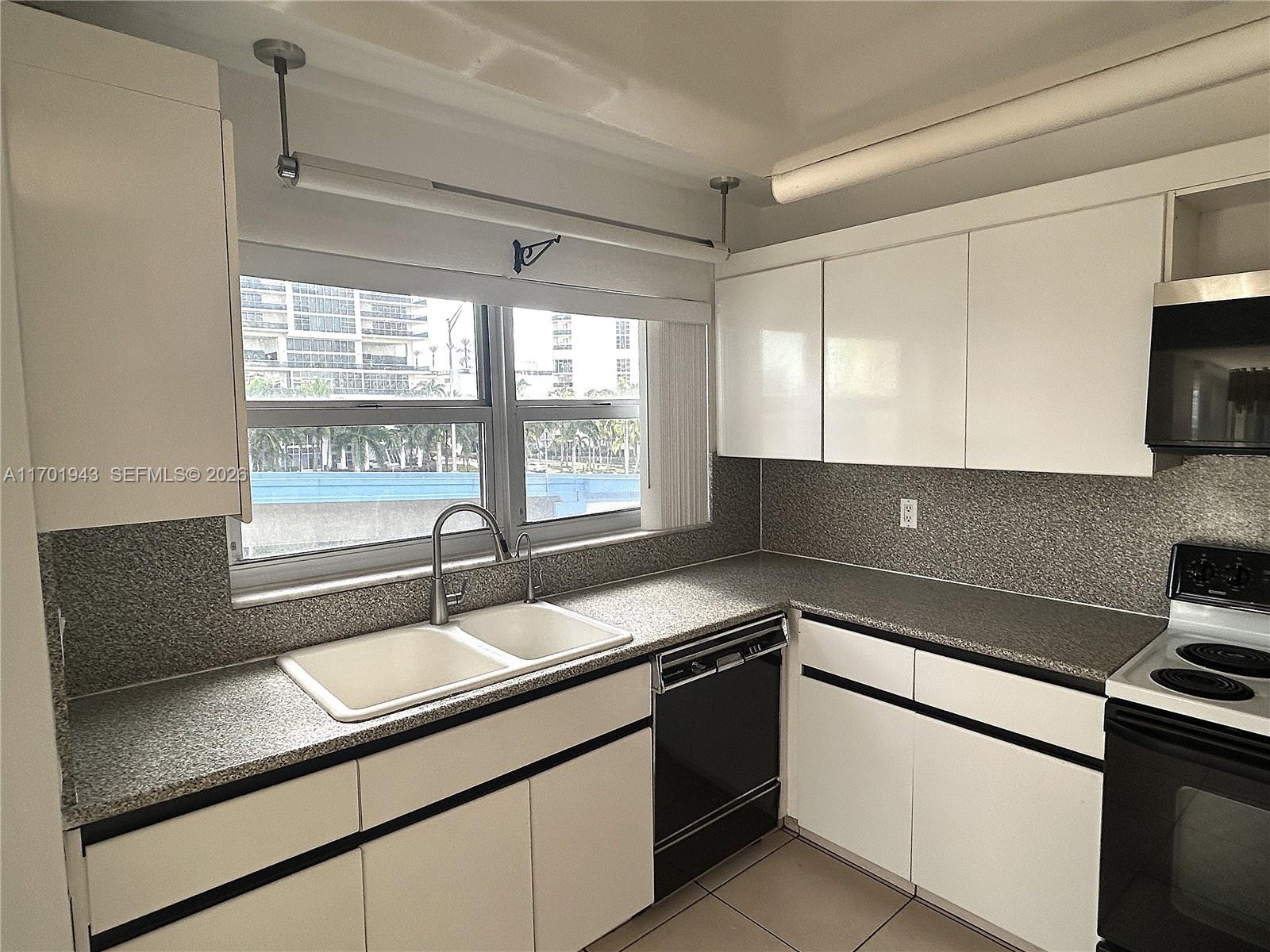 A kitchen features white cabinets, black appliances, granite countertops, and a palm tree door decal — 1825 S Ocean Dr # 401, Hallandale Beach FL 33009, HALLANDALE BEACH, FL
