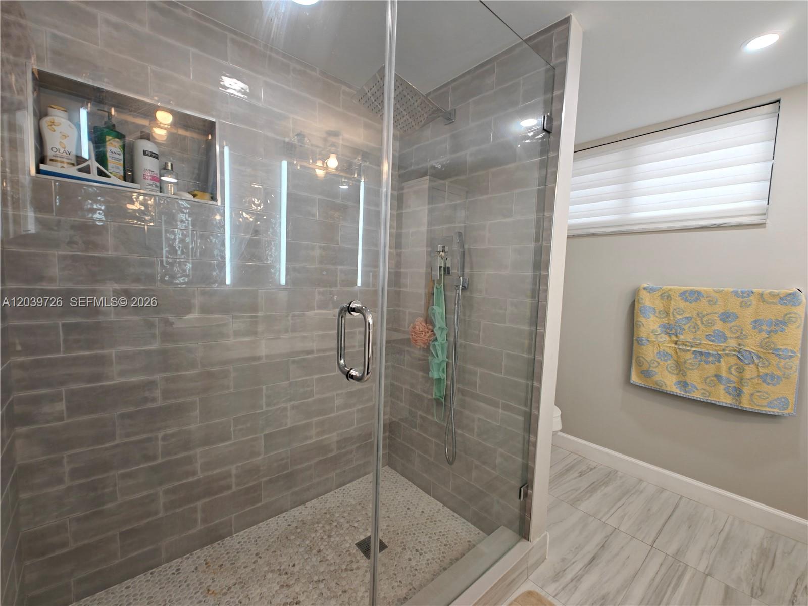 A walk-in shower with gray subway tiles, a pebble floor, and a glass door — 601 Ives Dairy Rd # 8, Miami FL 33179, MIAMI, FL