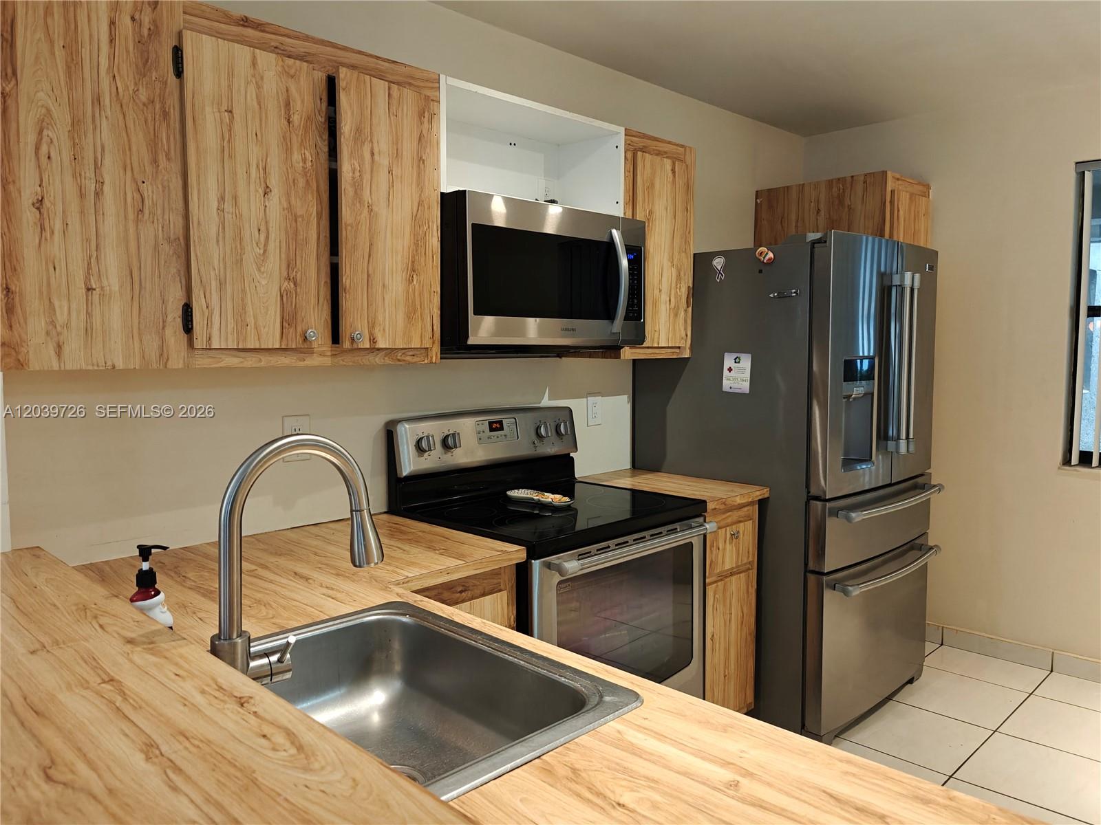 A kitchen features wood-grain cabinets, stainless steel appliances, and a stainless steel sink — 601 Ives Dairy Rd # 8, Miami FL 33179, MIAMI, FL