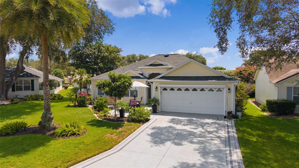 A yellow single-story house with a two-car garage and a paved driveway — 9340 SE 170TH HUMPHREYS LOOP, THE VILLAGES, FL