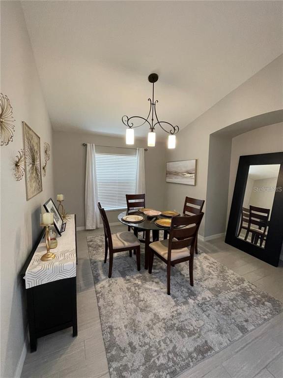 A dining room features a round glass table, four chairs, a chandelier, and a large mirror — 15142 MASTHEAD LANDING CIRCLE, WINTER GARDEN, FL