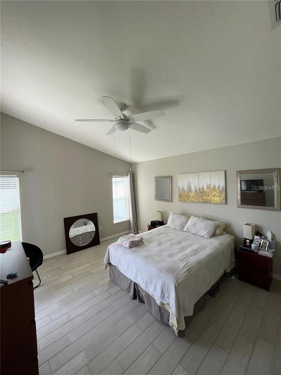 A bedroom features light-colored tile flooring, a ceiling fan, and a bed against a wall — 15142 MASTHEAD LANDING CIRCLE, WINTER GARDEN, FL