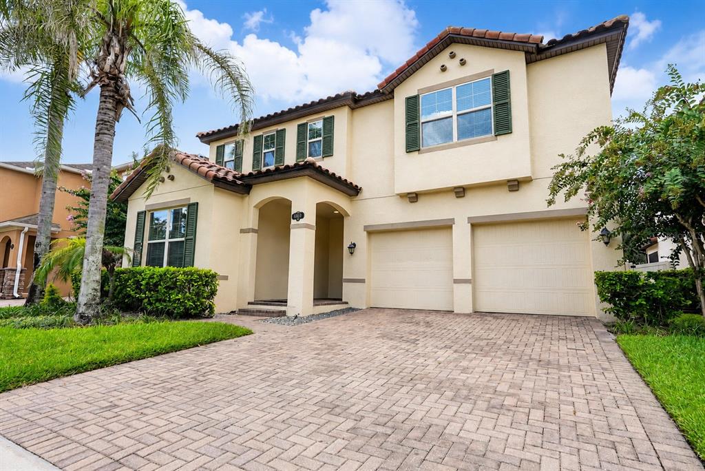 A two-story stucco house with a paver driveway, two-car garage, and green shutters — 9088 OUTLOOK ROCK TRAIL, WINDERMERE, FL