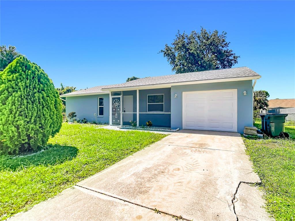 A light blue single-story house features a white garage door and a concrete driveway — 4441 MULGRAVE AVENUE, NORTH PORT, FL