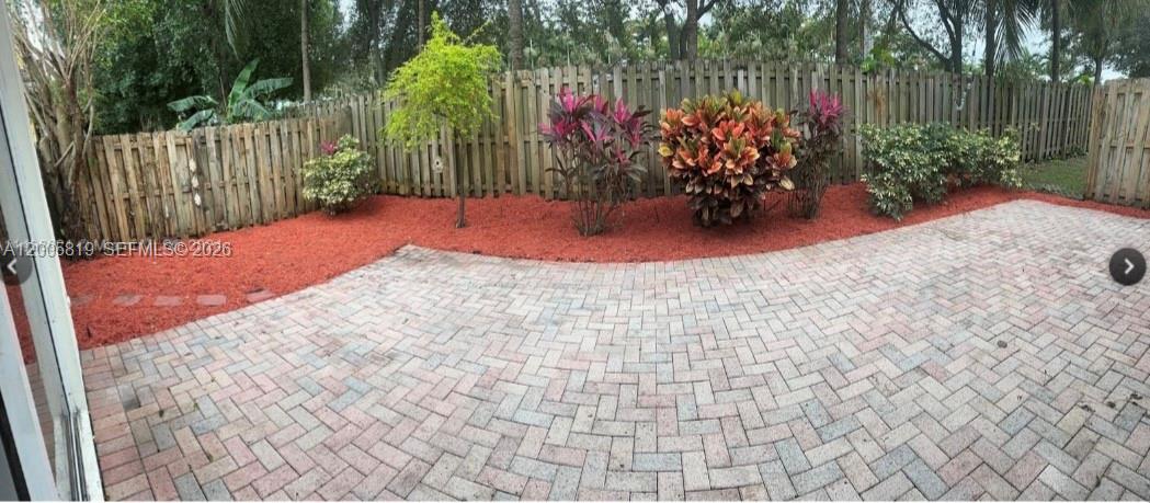 A paved patio overlooks a backyard with red mulch, various shrubs, and a wooden fence — 4268 NE 9th St, Homestead FL 33033, HOMESTEAD, FL