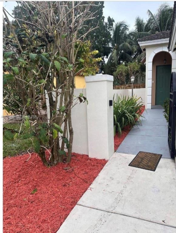 A concrete walkway leads to a green front door beside a white stucco wall — 4268 NE 9th St, Homestead FL 33033, HOMESTEAD, FL