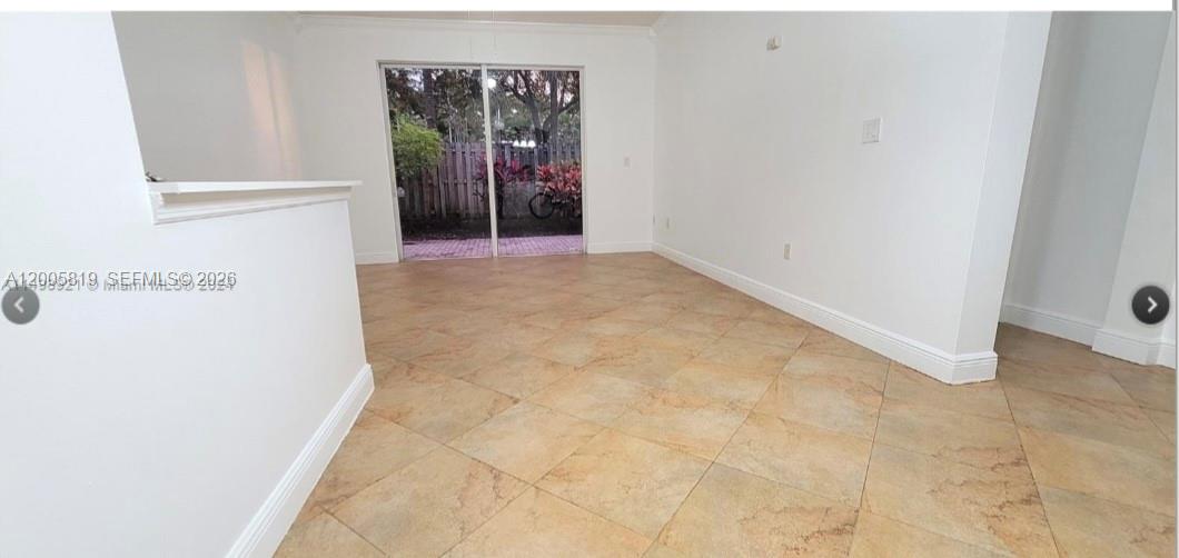 An empty room with tan tile flooring and a sliding glass door leading outside — 4268 NE 9th St, Homestead FL 33033, HOMESTEAD, FL