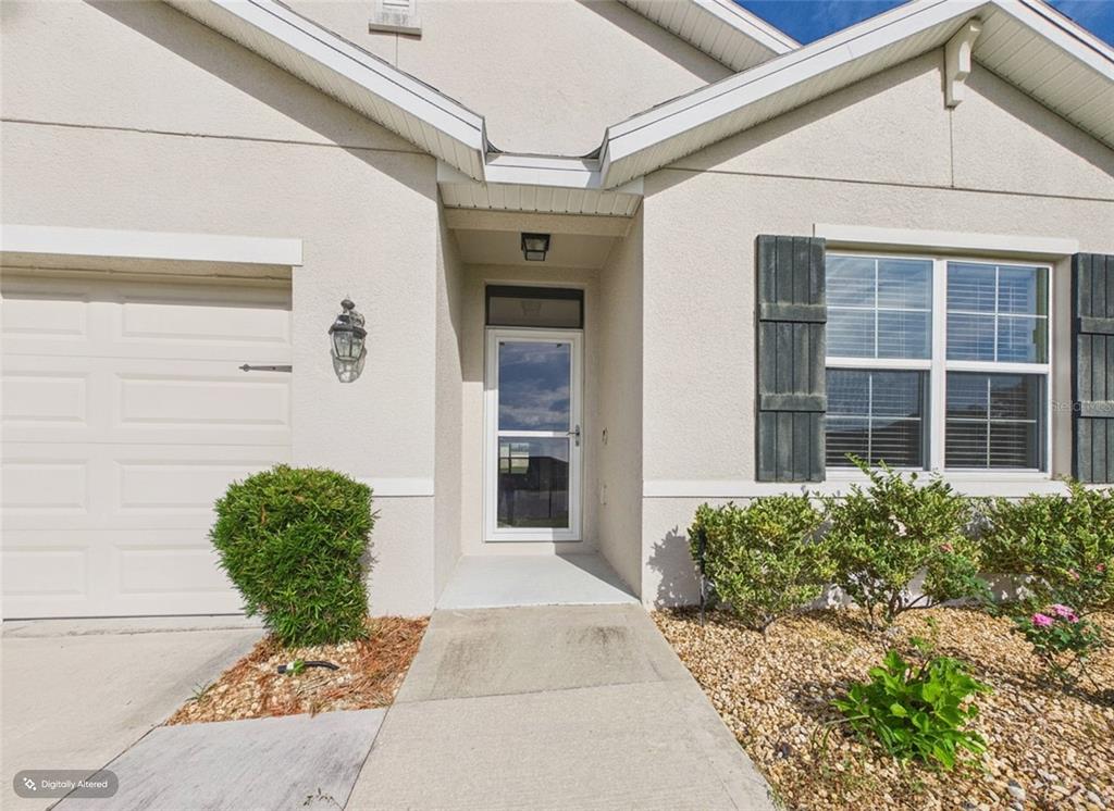 The exterior of a house features a garage, a front entrance, and a window — 4942 SW 97TH LANE, OCALA, FL