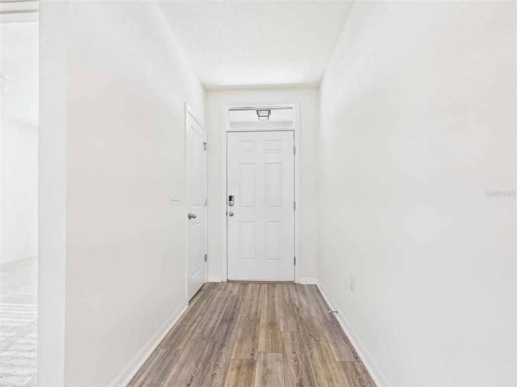 A white front door with a transom window sits at the end of a hallway — 4942 SW 97TH LANE, OCALA, FL