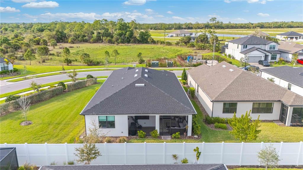 An aerial view shows the back of a house with a screened-in patio and yard — 2414 GABEL OAK DRIVE, NORTH PORT, FL