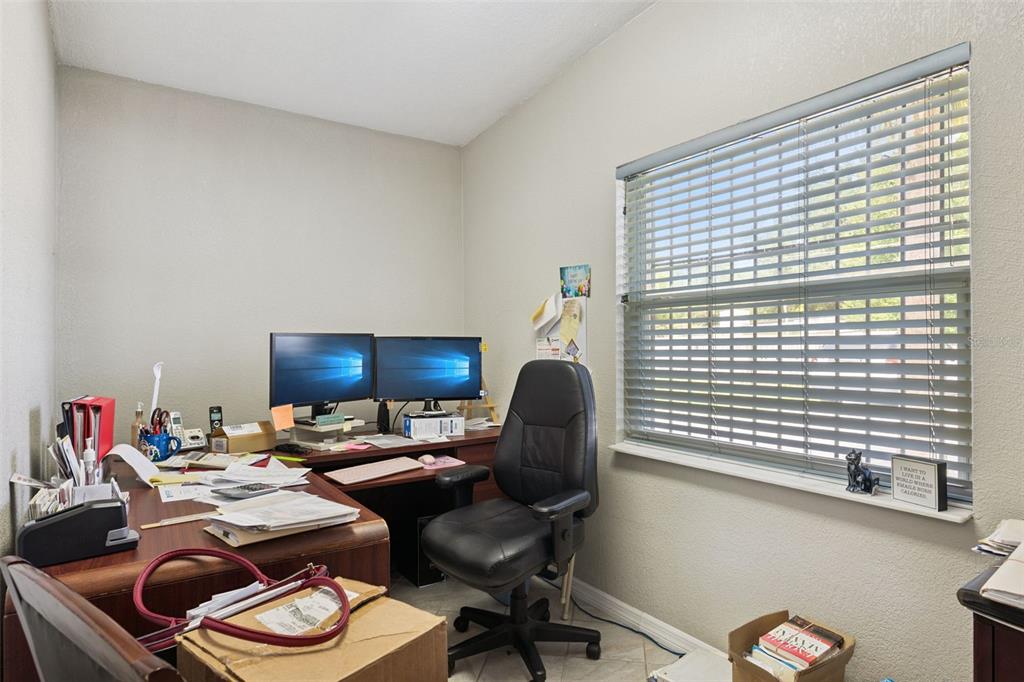 A home office features a wooden desk, two computer monitors, a black chair, and a window — 36 S SEMORAN BOULEVARD, ORLANDO, FL