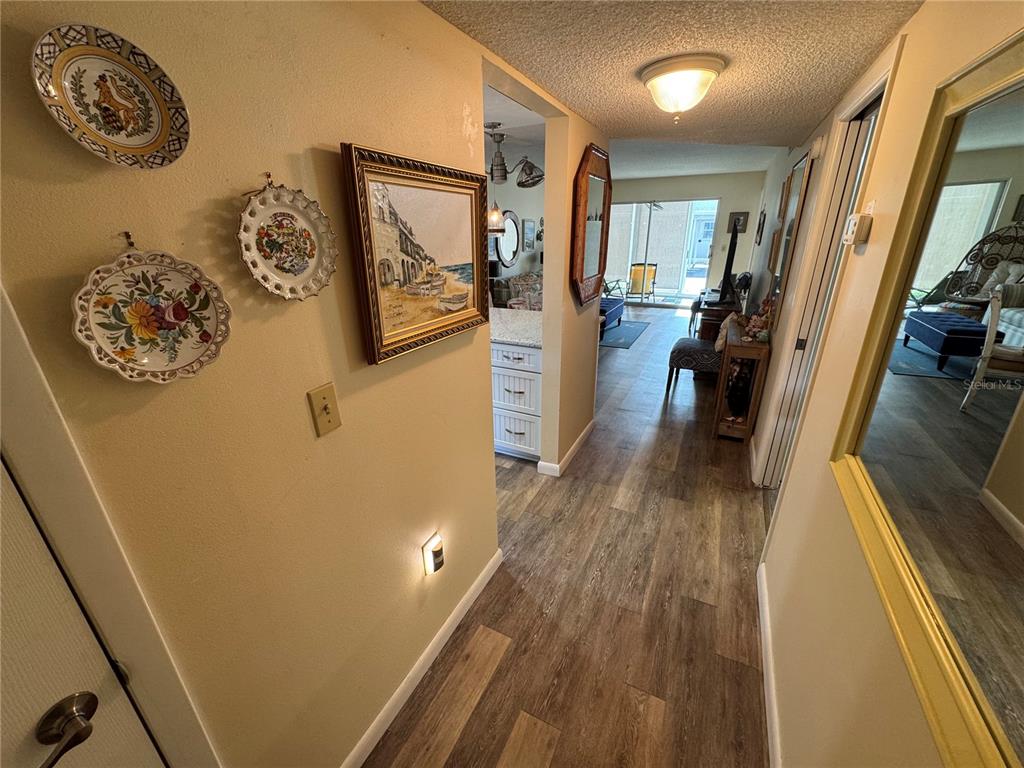 A hallway with wood-look flooring leads to a living area with a sliding glass door — 1400 TARPON CENTER DRIVE UNIT 111, VENICE, FL
