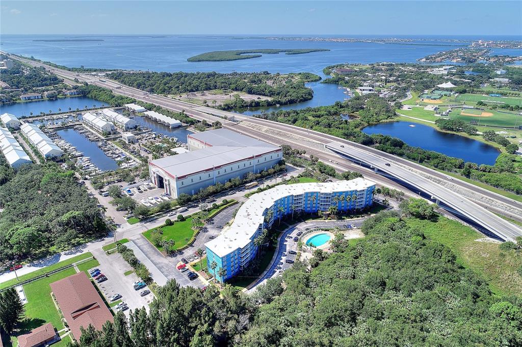 An aerial view shows a blue apartment building, a marina, and a highway near water — 3315 58TH AVENUE S UNIT 513, ST PETERSBURG, FL