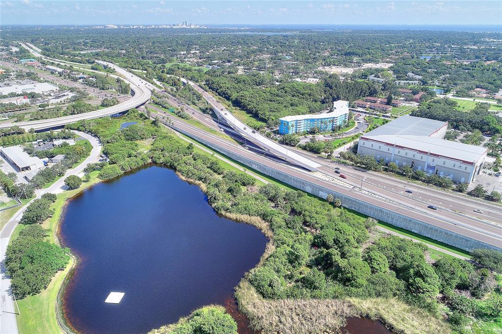 An aerial view shows a highway overpass, a large pond, and nearby commercial buildings — 3315 58TH AVENUE S UNIT 513, ST PETERSBURG, FL