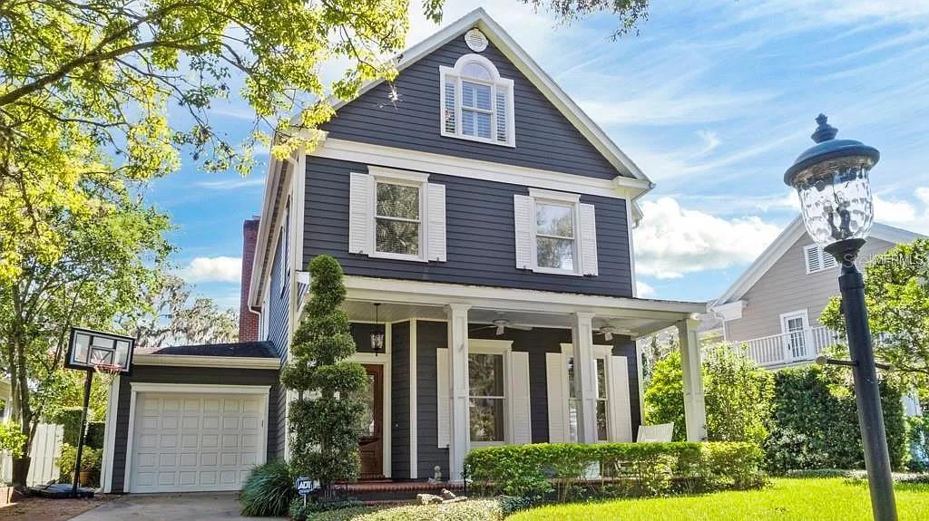 A two-story dark blue house with white trim, a front porch, and an attached garage — 1119 BELLEAIRE CIRCLE, ORLANDO, FL