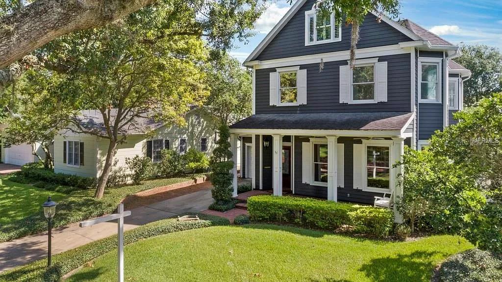 A two-story dark gray house with white trim and a front porch sits on grass — 1119 BELLEAIRE CIRCLE, ORLANDO, FL
