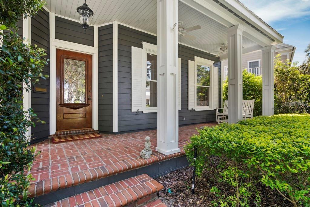 A front porch with brick flooring, white columns, and a dark wood door with glass — 1119 BELLEAIRE CIRCLE, ORLANDO, FL