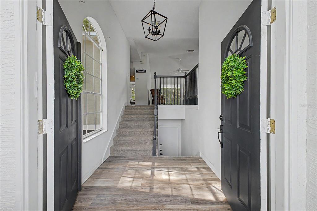 A two-story house with a concrete driveway and a neighboring modern home on a lawn — 8010 GULF WAY, HUDSON, FL