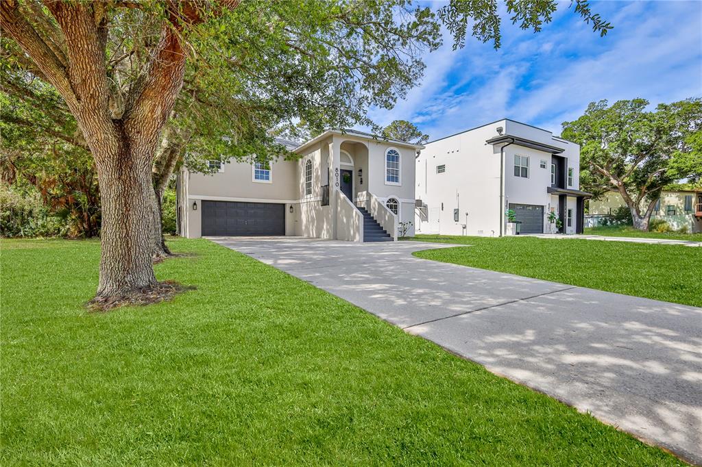 A two-story house with a raised entryway, gray exterior, and a concrete driveway — 8010 GULF WAY, HUDSON, FL