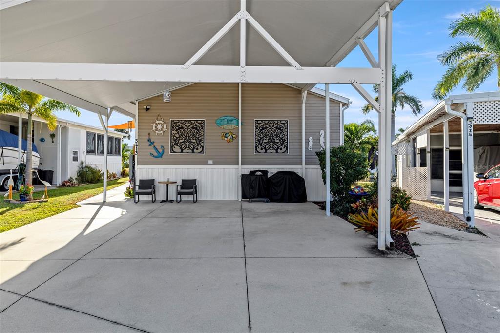 A concrete driveway leads to a covered carport area in front of a tan house — 3413 BAYSIDE PARKWAY, PUNTA GORDA, FL