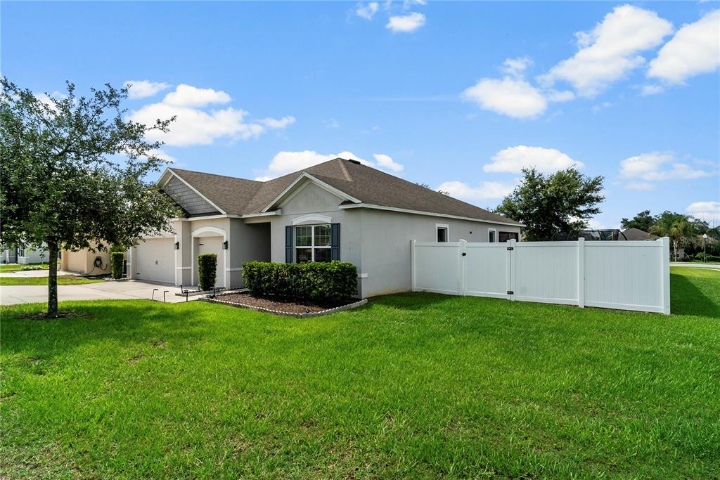 A single-story house with a gray exterior, a two-car garage, and a white vinyl fence — 15266 AQUARIUS WAY, MASCOTTE, FL
