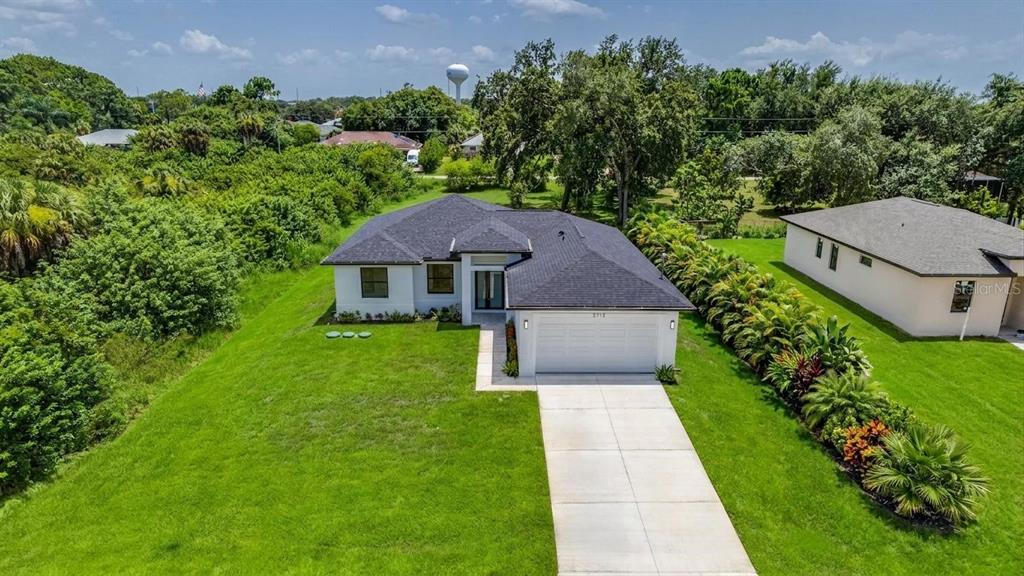 An aerial view of a single-story house with a white garage and a green lawn — 2713 8TH STREET W, LEHIGH ACRES, FL
