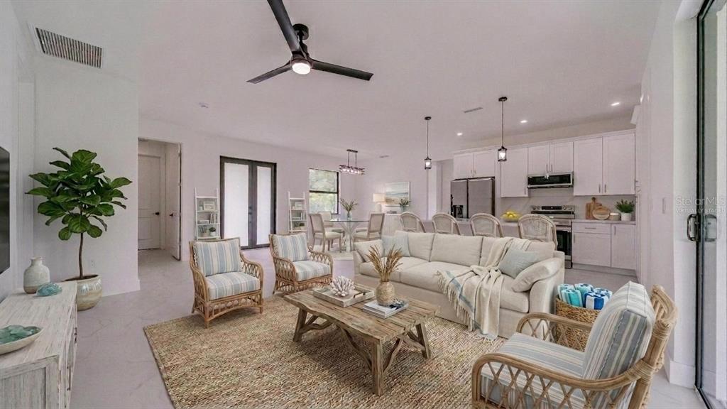 An open-concept living room and kitchen featuring light-colored furniture, a wooden coffee table, and tile — 2713 8TH STREET W, LEHIGH ACRES, FL