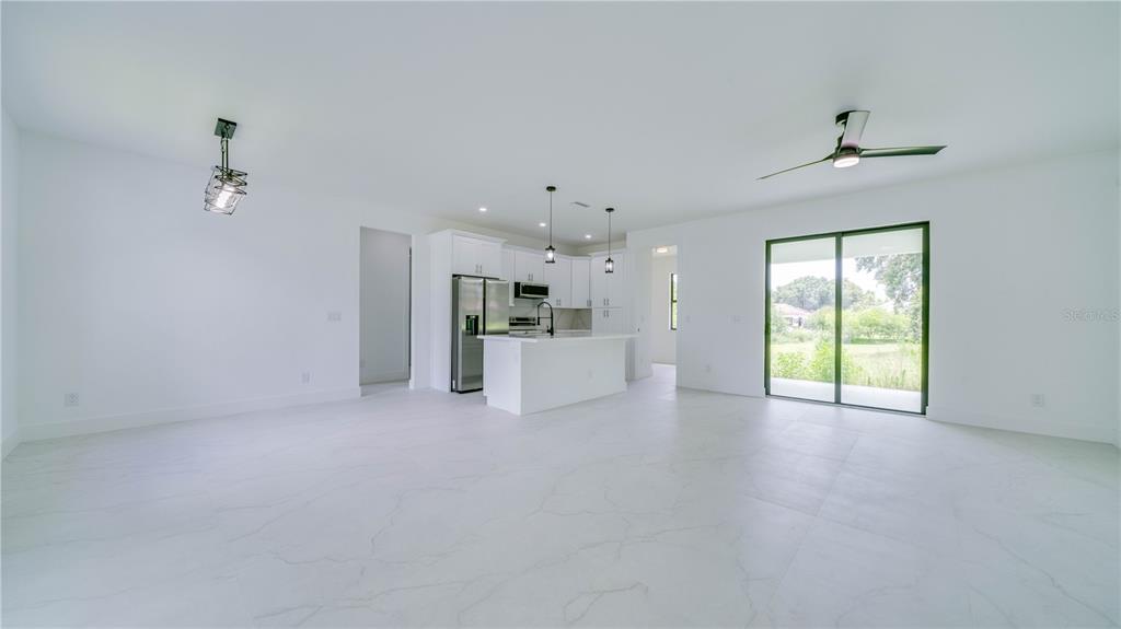 An open-concept kitchen and living area features white cabinetry, a center island, and tile flooring — 2713 8TH STREET W, LEHIGH ACRES, FL
