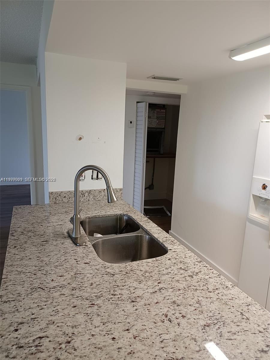 A kitchen island features a stainless steel double sink with a faucet and granite countertops — 16220 NW 2nd Ave # 411, Miami FL 33169, MIAMI, FL