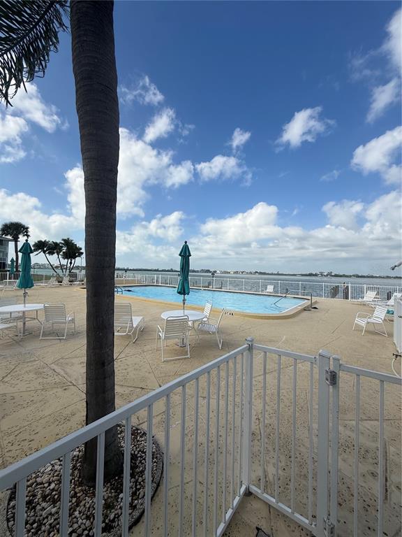 A swimming pool with lounge chairs and umbrellas overlooks a bay under a blue sky — 775 JOHN RINGLING BOULEVARD UNIT # 33, SARASOTA, FL