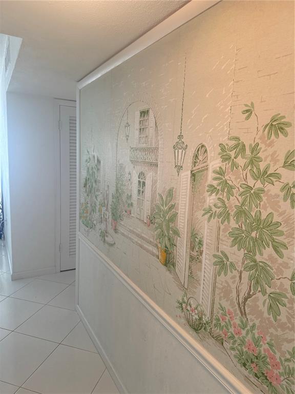 A hallway features white tile floors and a wall mural depicting a Mediterranean courtyard scene — 775 JOHN RINGLING BOULEVARD UNIT # 33, SARASOTA, FL
