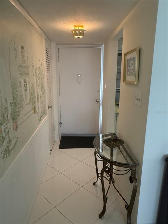 A tiled entryway features a glass-topped console table, a mural wall, and a white door — 775 JOHN RINGLING BOULEVARD UNIT # 33, SARASOTA, FL