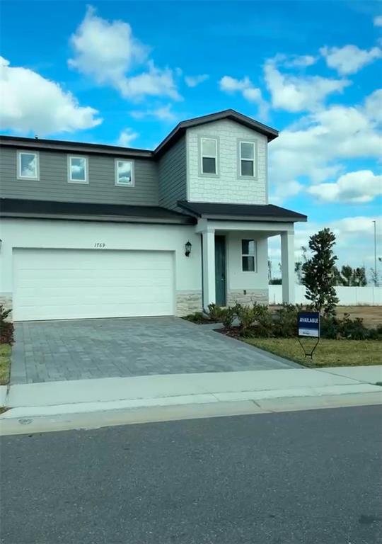 A two-story house features a white garage, gray siding, and a stone-accented entryway — 1769 ARCHER DRIVE, MINNEOLA, FL