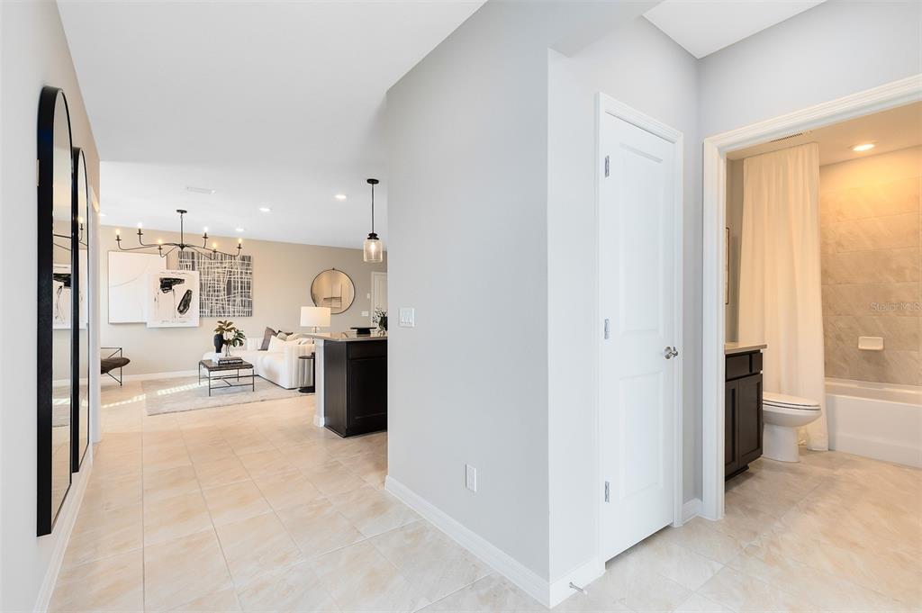 A hallway with tiled floors leads to a living room and a bathroom with a shower — 10933 HEATHER HAVEN STREET, ORLANDO, FL