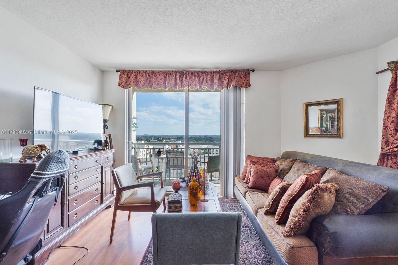 A living room features a sofa, wooden dresser, television, and a balcony with outdoor seating — 9055 SW 73rd Ct # 903, Miami FL 33156, MIAMI, FL