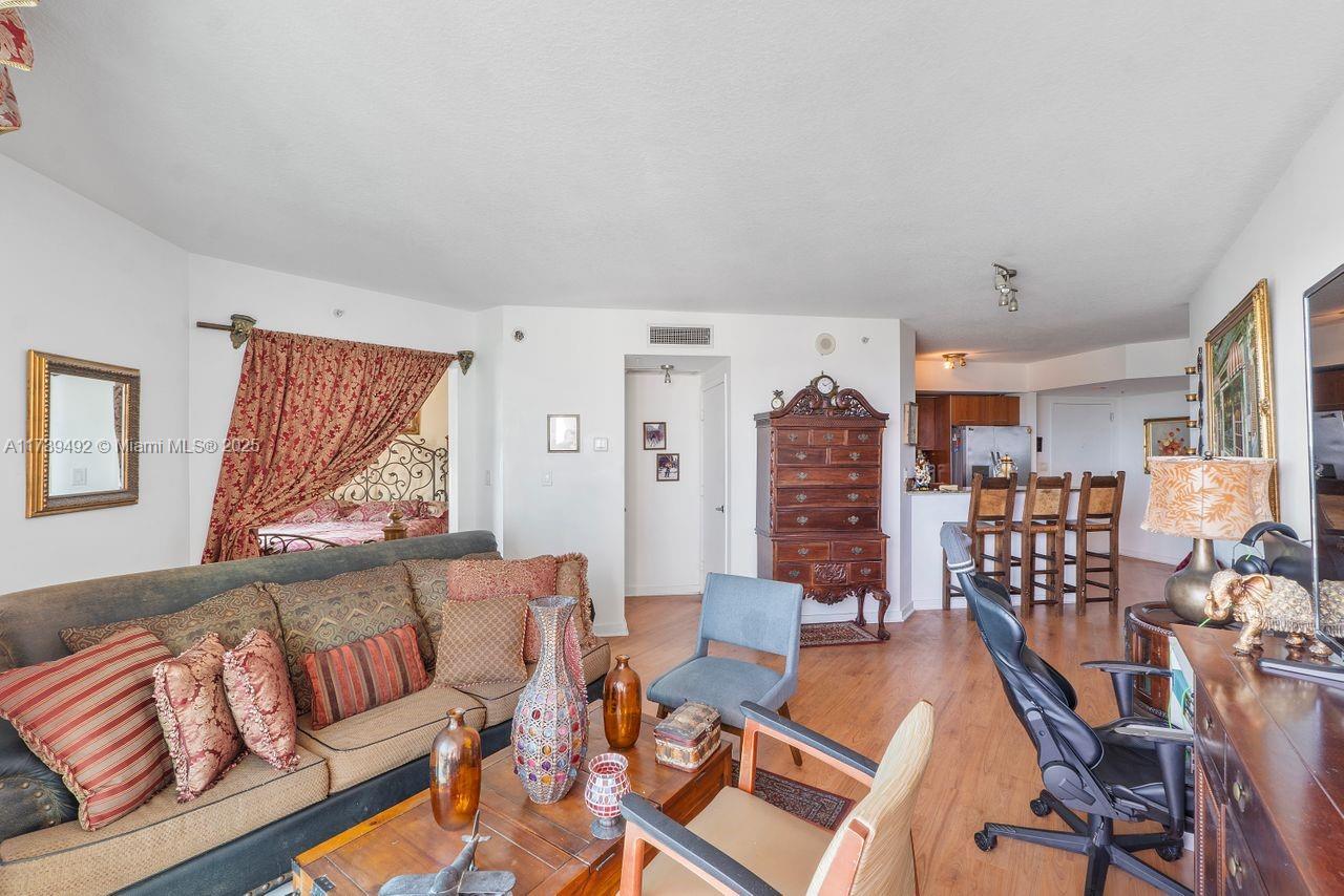 A living room features a sofa, wooden furniture, and an open view into a bedroom — 9055 SW 73rd Ct # 903, Miami FL 33156, MIAMI, FL
