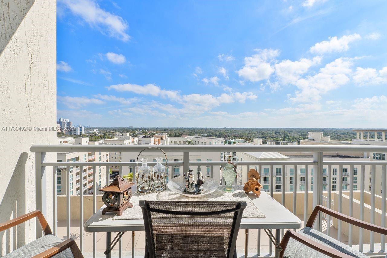 A balcony with a small table and chairs overlooks a city and landscape view — 9055 SW 73rd Ct # 903, Miami FL 33156, MIAMI, FL