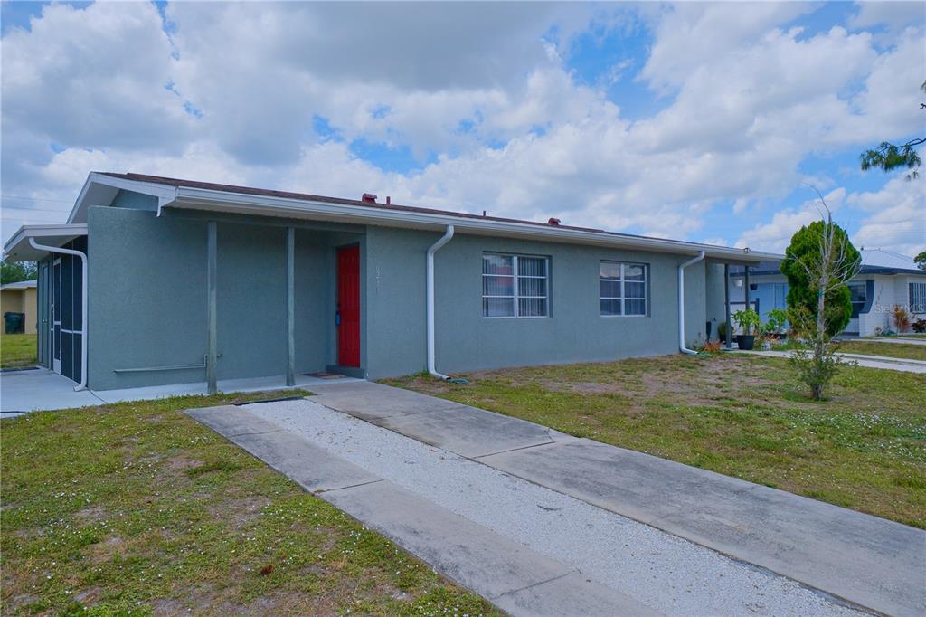 A single-story house with a gray stucco exterior, a red front door, and a driveway — 6231 CONISTON TERRACE, NORTH PORT, FL